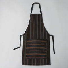 Stockka black apron with orange pinstripes, large front pocket, and adjustable neck strap. Made of poly-cotton blend.
