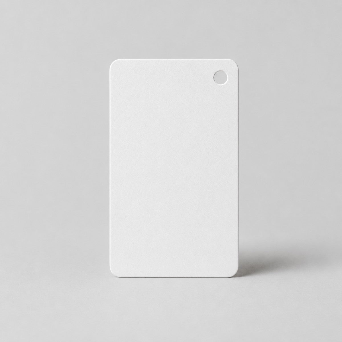 Stockka white blank rectangular hang tag with rounded corners and a hole punch at the top right corner.
