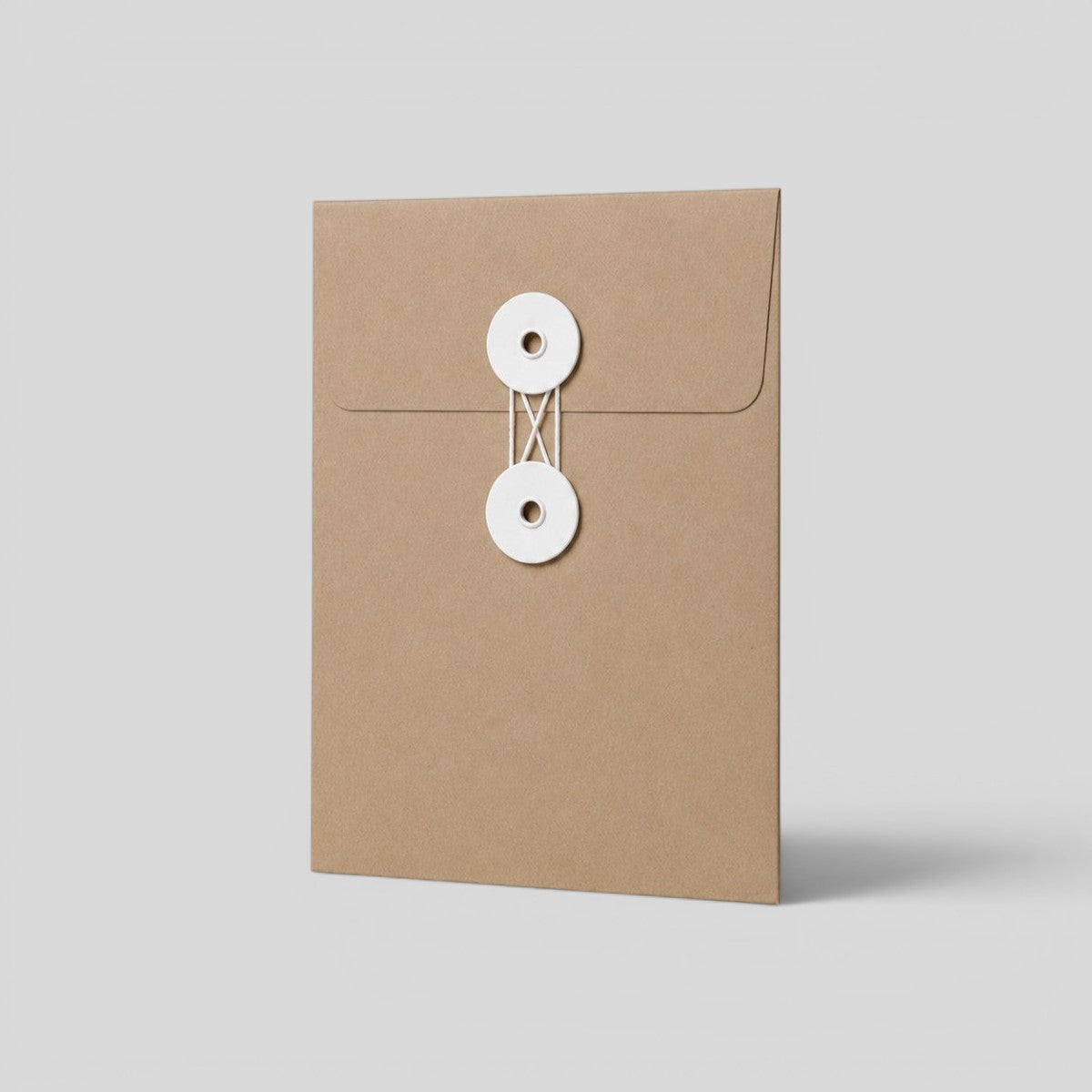 Stockka brown kraft paper envelope with white string and disc closure, ideal for documents and invitations.