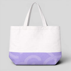 Stockka white canvas tote bag with a purple graphic print on the bottom and long handles for shoulder wear.
