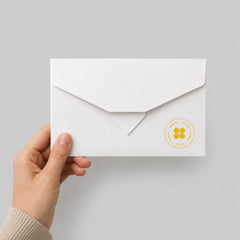 Stockka classic white flat envelope with triangular flap, made of 300g matte coated paper, held in a hand.