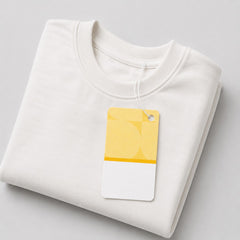 Stockka custom branded clothing tag on a folded white sweatshirt. The tag is yellow and white with a graphic design.