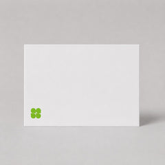 Stockka minimalist white 350gsm matte cardstock flat greeting card with a small green clover logo icon.