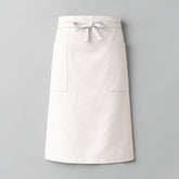 Stockka long white cotton-polyester blend waist apron with two side pockets and tie closure, ideal for restaurants and cafes.