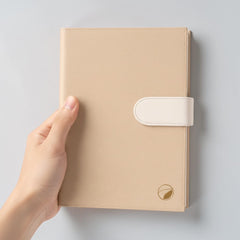 Stockka luxury beige hardcover notebook with magnetic closure and 80 lined pages. Features a subtle gold leaf logo.