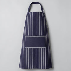 Stockka navy blue and white striped full-length apron with adjustable neck strap and front pocket. Cotton-polyester blend.