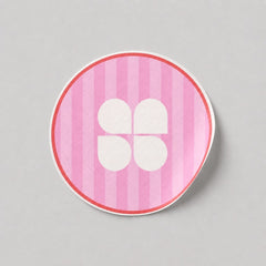 Stockka pink striped round sticker with a white four-petal flower logo and red border.