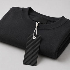Stockka black rectangular hang tag with diagonal stripes attached to a dark grey crewneck sweatshirt.