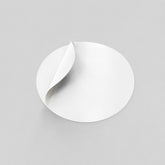 Stockka white round custom sticker with a peeled corner, made of coated sticker paper.