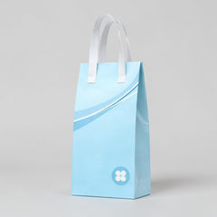 Stockka tall light blue kraft paper gift bag with white handles and a subtle wave design.
