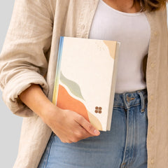 Stockka vertical hard cover notebook with abstract wavy design in cream, orange, green, and blue. 220 lined pages.