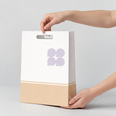 Stockka white kraft paper retail bag with cut-out handles and a beige bottom section.