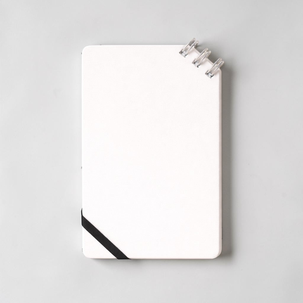 Stockka compact white spiral notebook with black elastic closure and 80 lined pages.