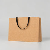 Stockka wide kraft paper gift bag with reinforced base and flat fabric handles, ideal for retail and premium packaging.