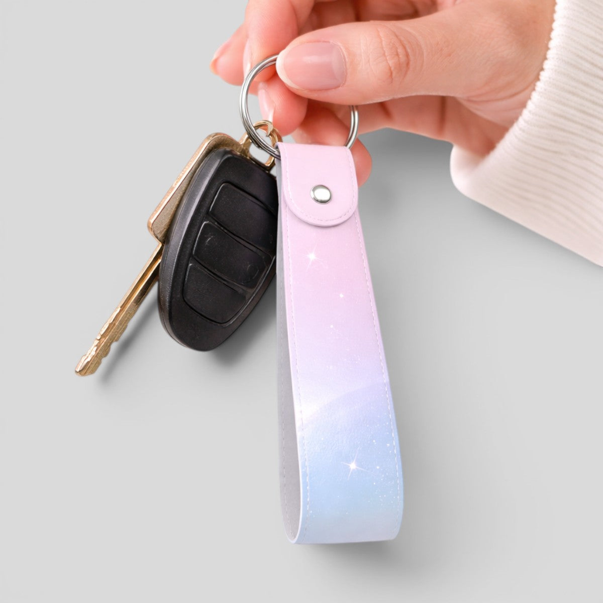 Stockk customisable loop keychain with gradient pink and blue faux leather and metal ring holding car keys.