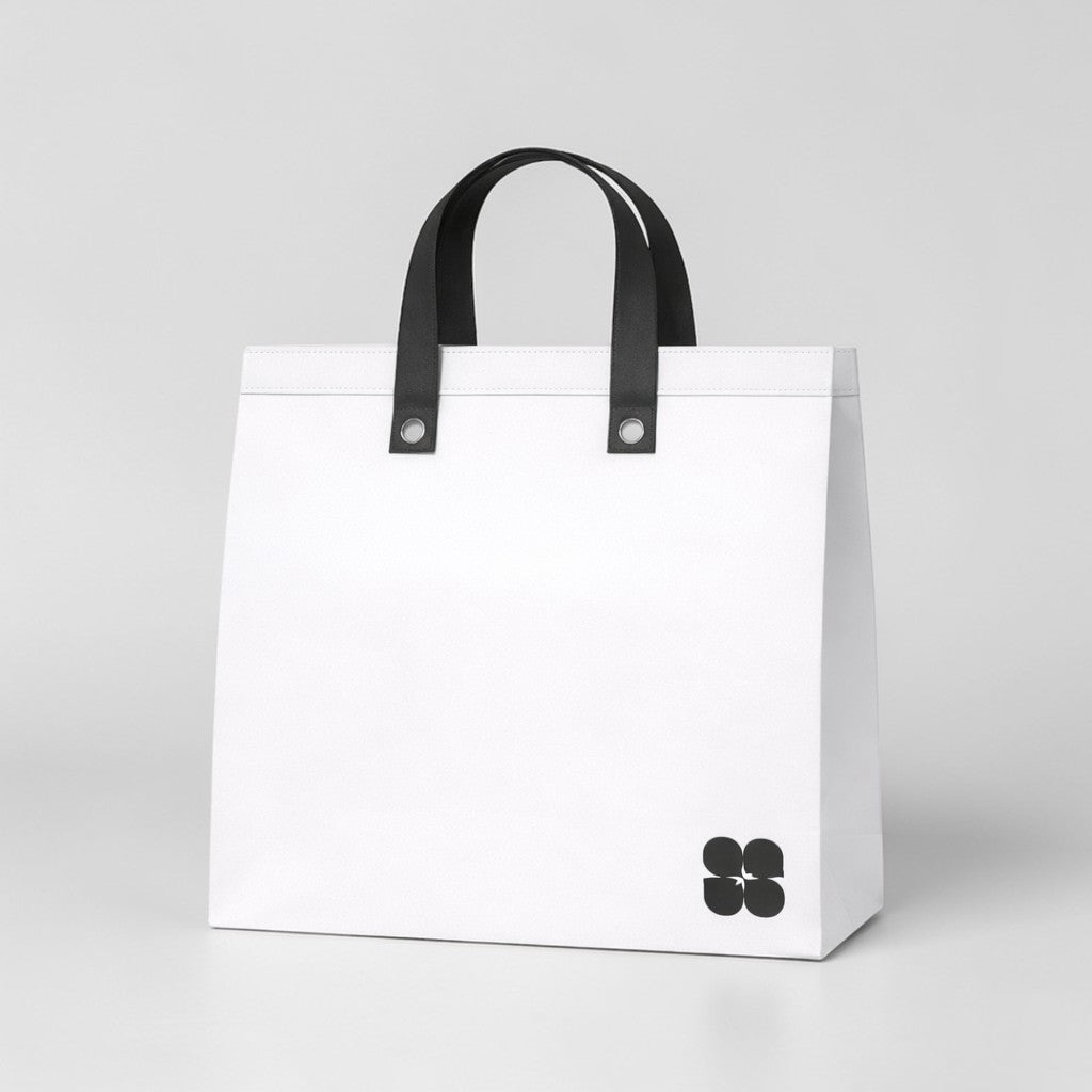 Stockk large white non-woven polypropylene tote bag with black handles and a small black logo on the bottom right.