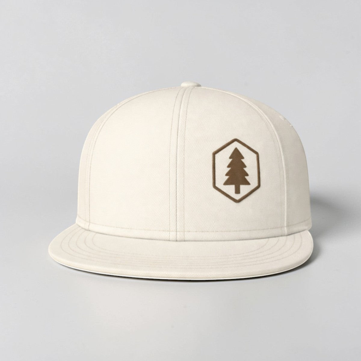 Stockk snapback hat in off-white cotton with a flat brim and a hexagonal patch featuring a brown tree logo.