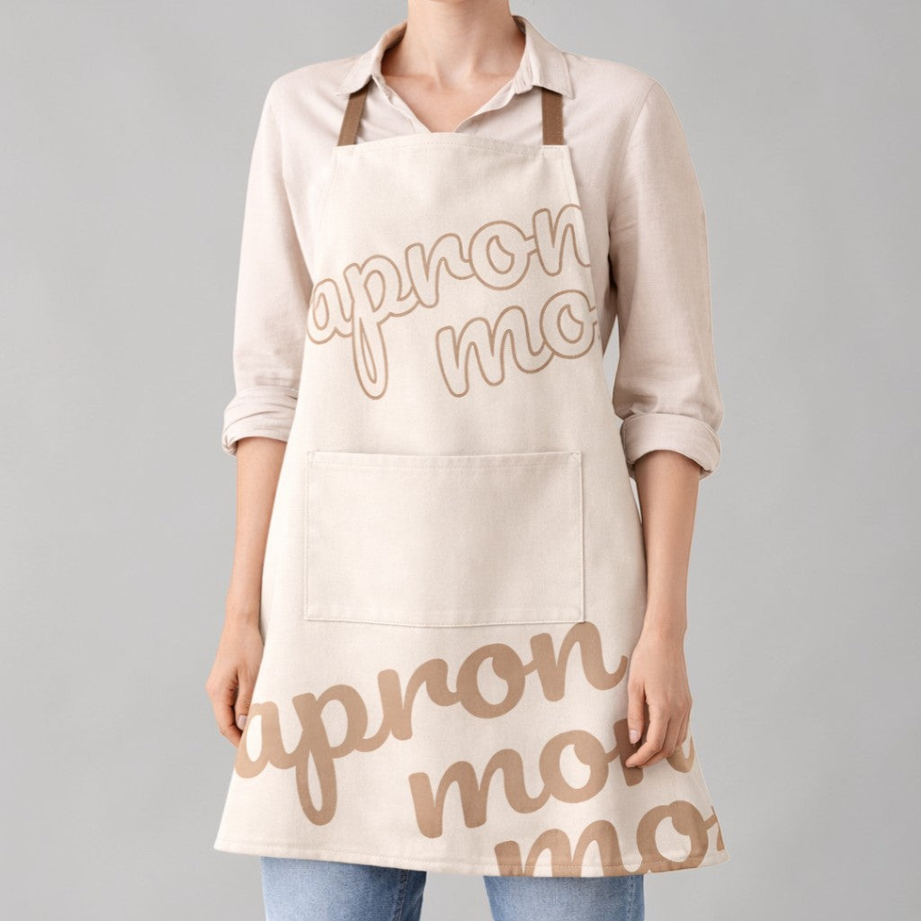 Stockka full length apron in beige cotton-polyester blend with cross straps and front pocket. Features 'apron mo' text graphic.