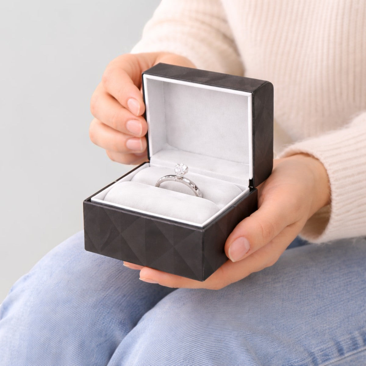 Stockka black textured jewelry box with soft white interior, holding a diamond ring. Customizable for branding or gifts.