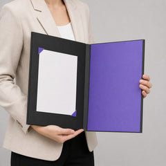 Stockka black hard cover presentation folder with purple interior and internal notepad, held by a person in a beige blazer.