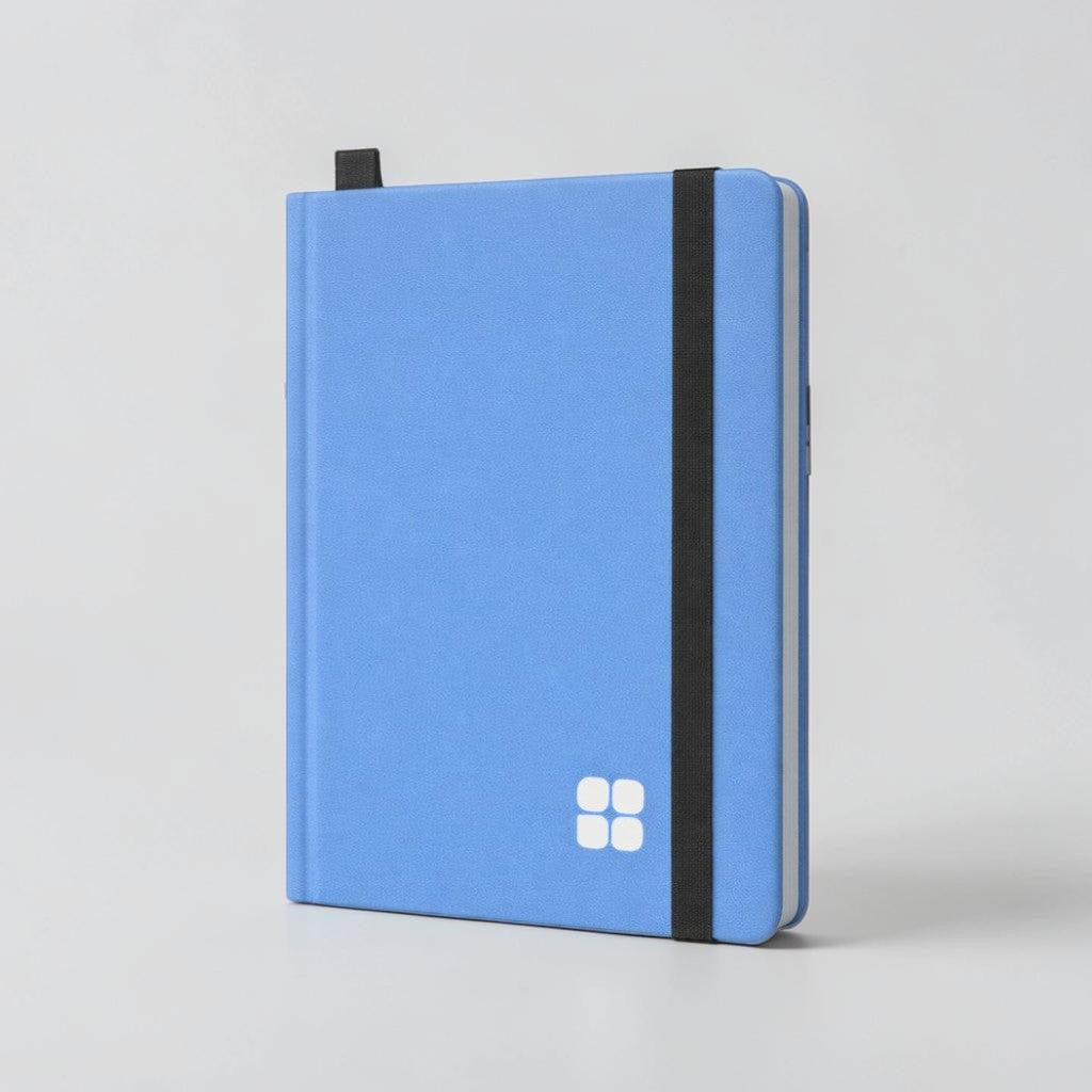 Stockka blue soft cover notebook with elastic closure, ribbon bookmark, and 80 lined pages. Features a white four-square logo.