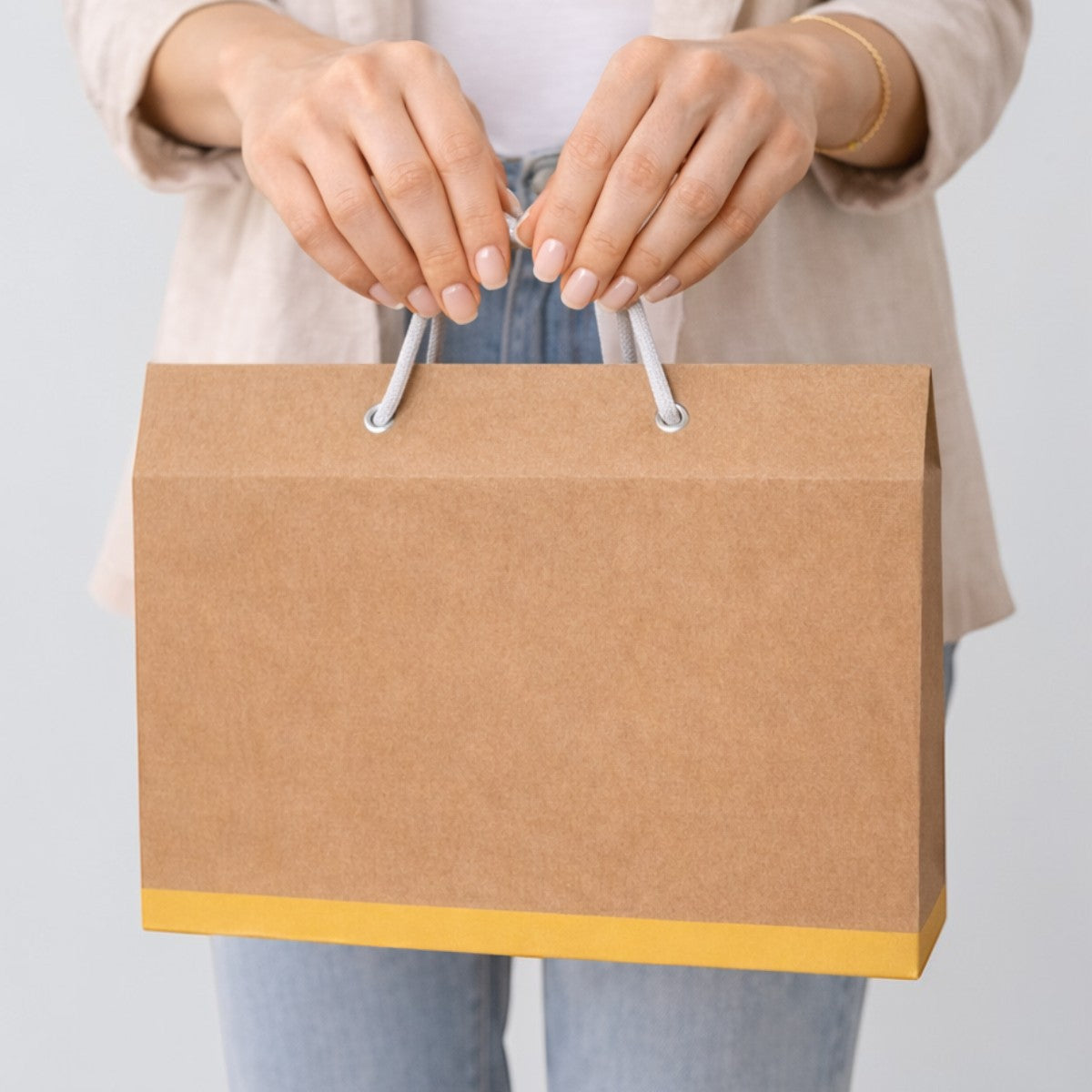 Stockka brown kraft paper gift box with rope handle and yellow accent band, ideal for boutique items.
