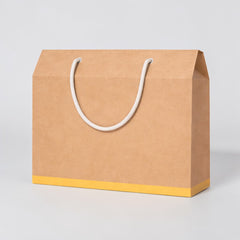 Stockka brown kraft paper gift box with white rope handle and yellow base, ideal for boutique items.