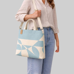 Stockka light blue and cream geometric print canvas messenger bag with top handles and adjustable strap.