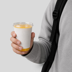 Stockka narrow clear plastic cup with flat lid, white wavy sleeve, holding orange beverage. Ideal for takeaway.