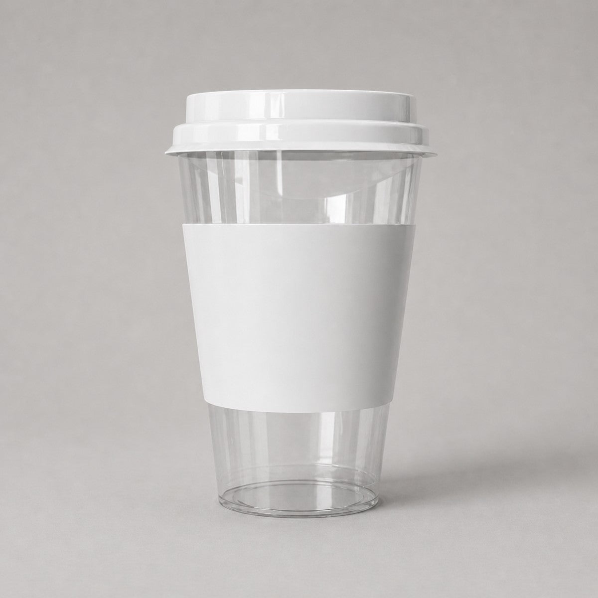 Stockka clear PET plastic cup with white cardboard sleeve and flat lid, ideal for cold drinks and takeaway.