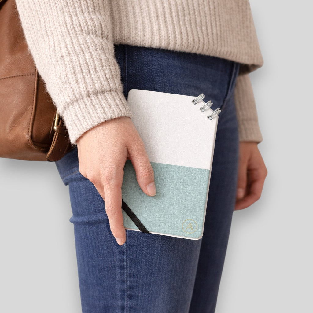 Stockka compact notebook with spiral binding on the corner, elastic closure, and custom design. Features 80 lined pages and a soft cover.