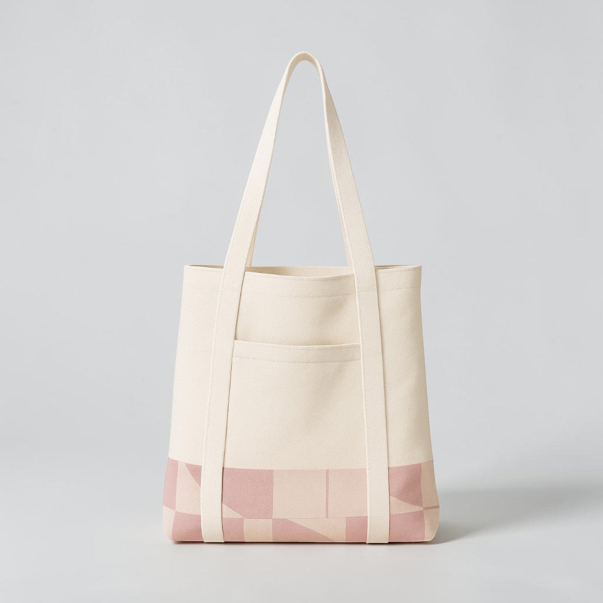 Stockka cream canvas tote bag with pink geometric pattern on bottom and front pocket. Long shoulder straps.