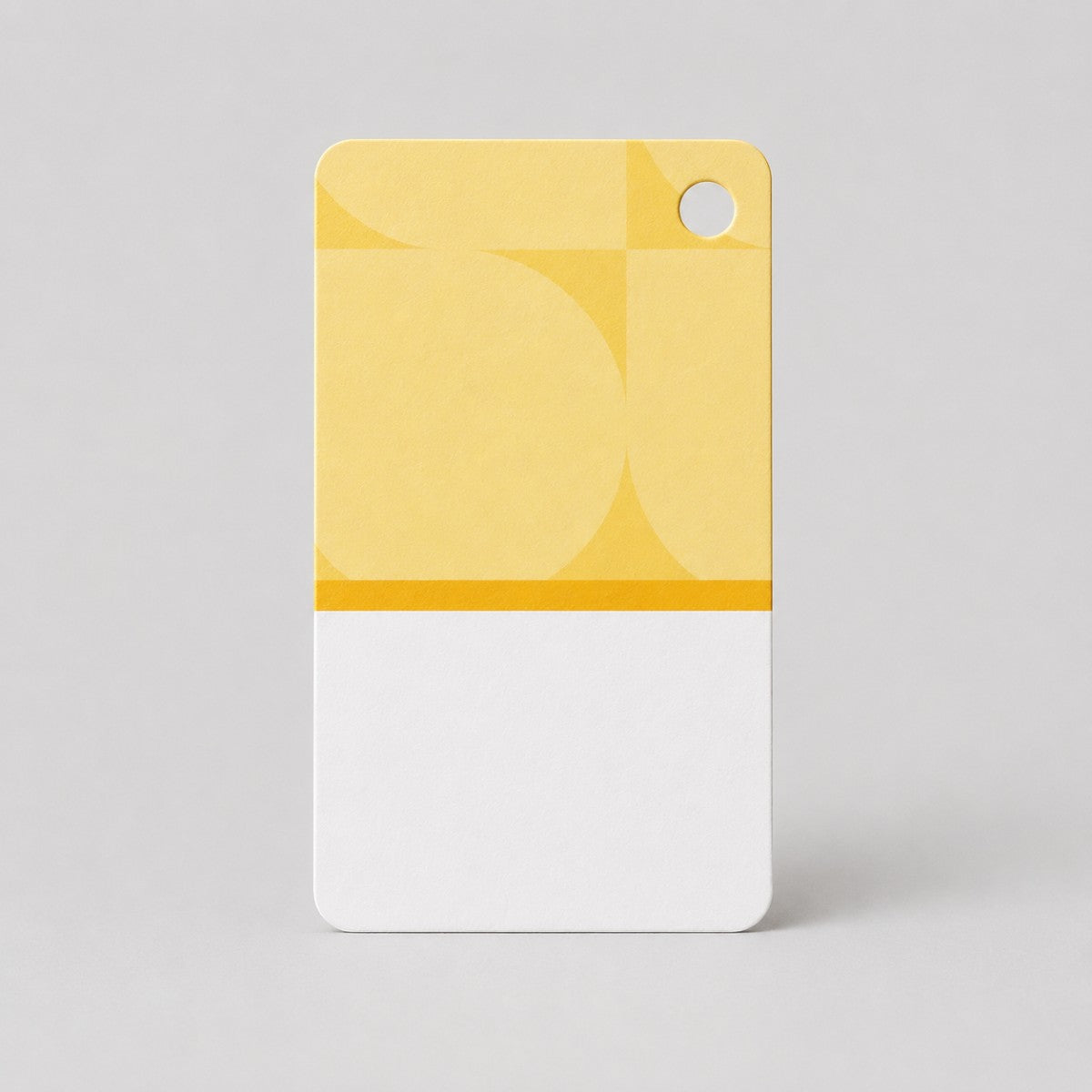 Stockka custom branded clothing tag, yellow and white with geometric pattern and hole for hanging.