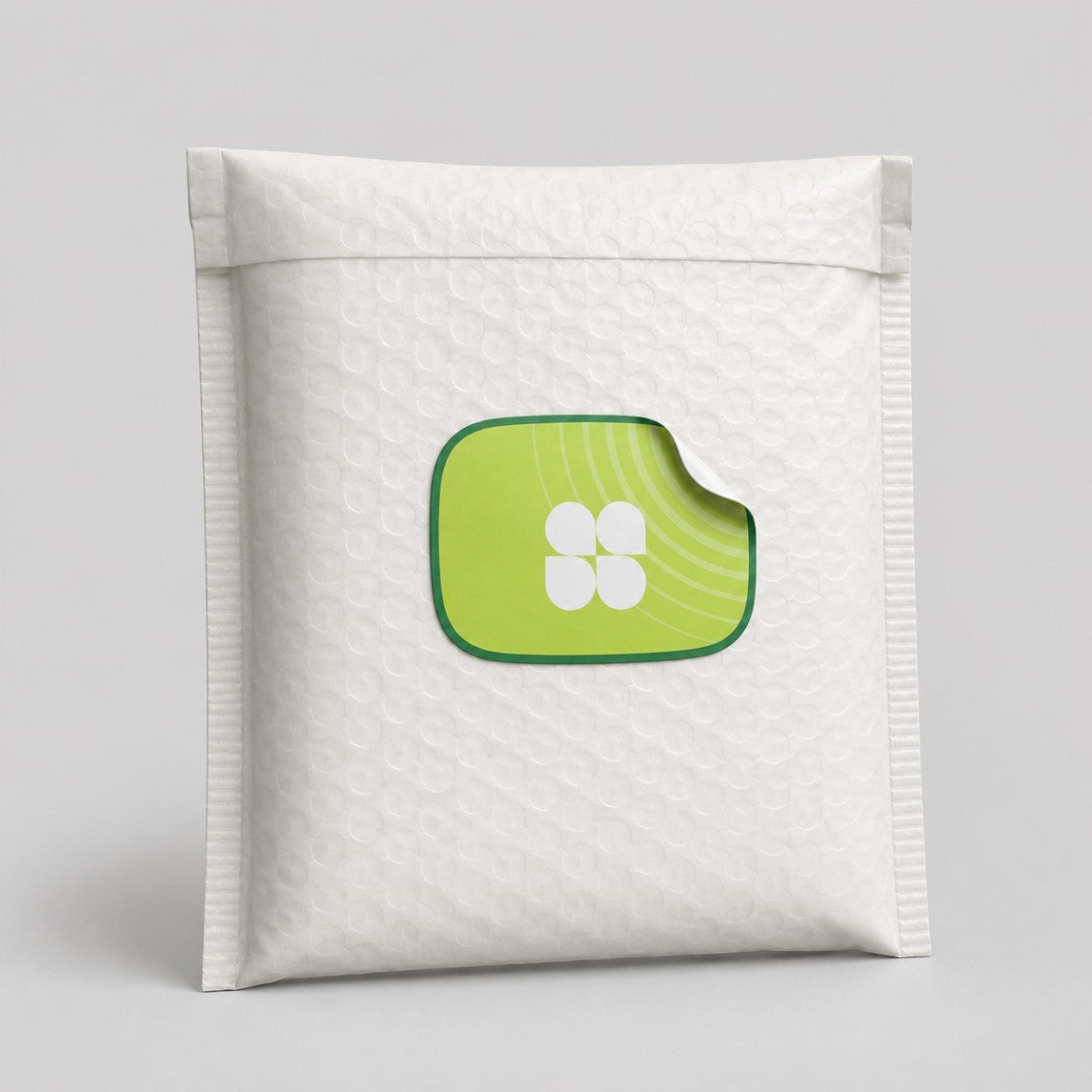 Stockka custom die-cut sticker with a green border and a white four-petal flower design on a white bubble mailer.