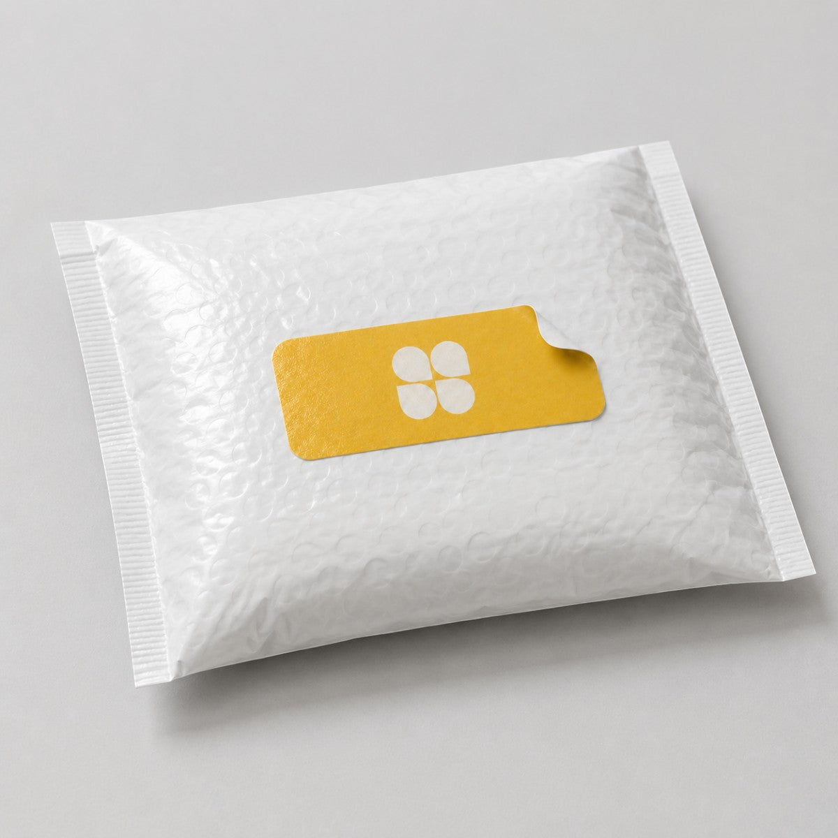 Stockka custom rectangular sticker with rounded corners and a peel tab, featuring a white four-petal logo on a yellow background.