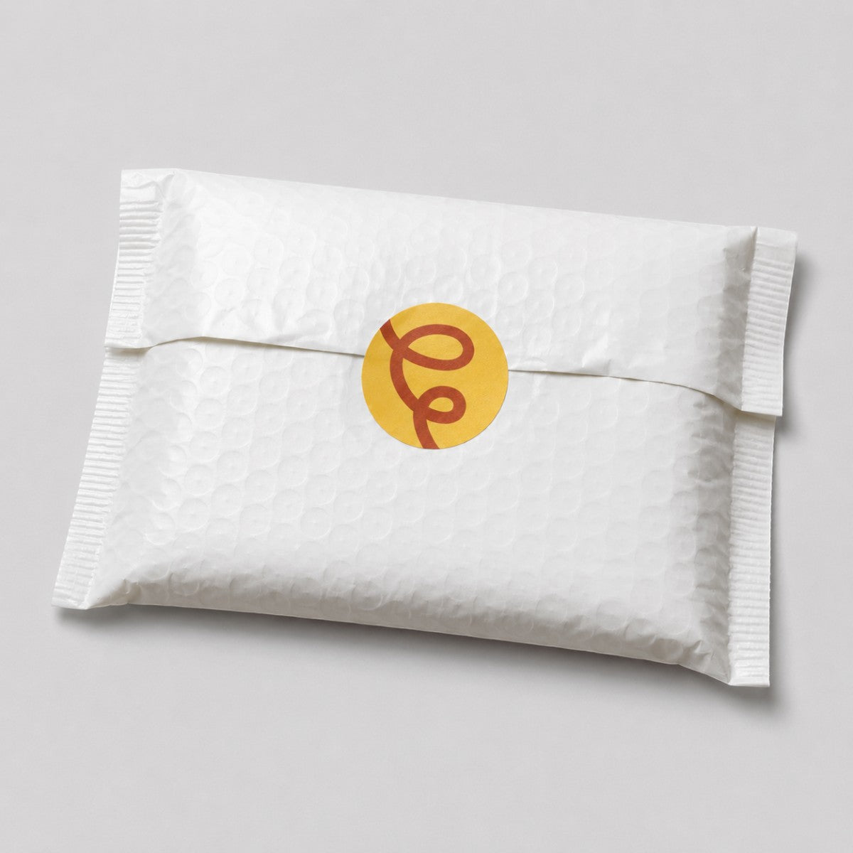 Stockka custom round sticker with a red swirl design on a white padded envelope.