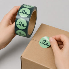 Stockka custom round stickers in mint green with a black swirl logo, perfect for branding products and packaging.