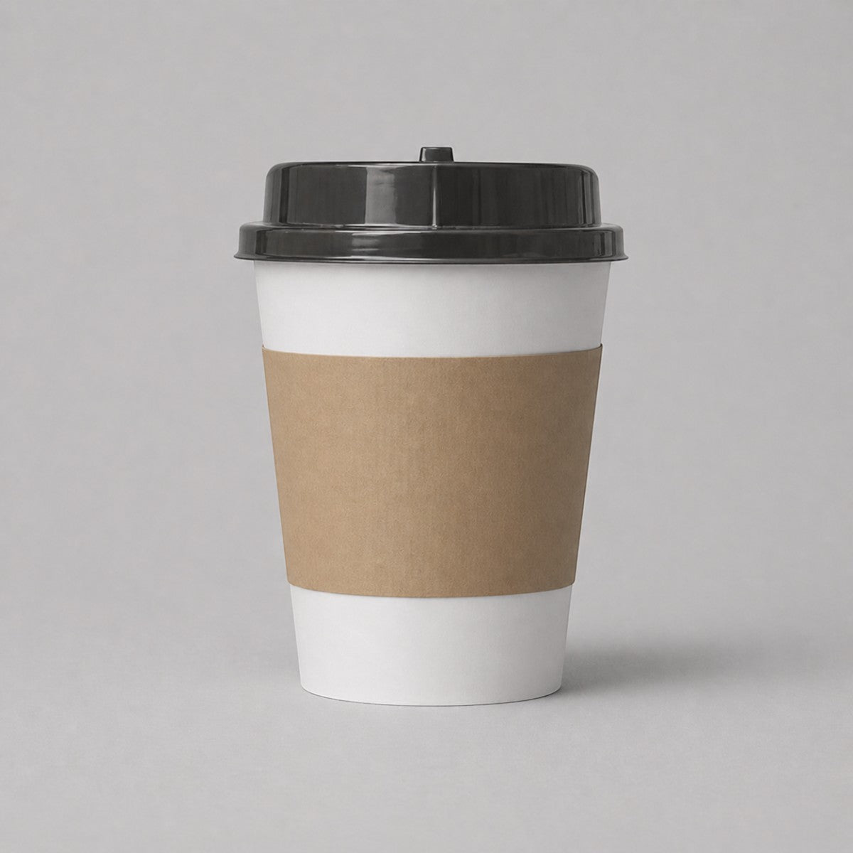 Stockka double-walled white paper coffee cup with black lid and brown kraft paper sleeve for hot beverages.