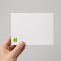 Stockka white matte 350gsm flat greeting card held in hand, featuring a minimalist green clover logo design.