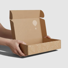 Stockka wide folding mailer box made of recycled cardboard with a leaf pattern and a logo.