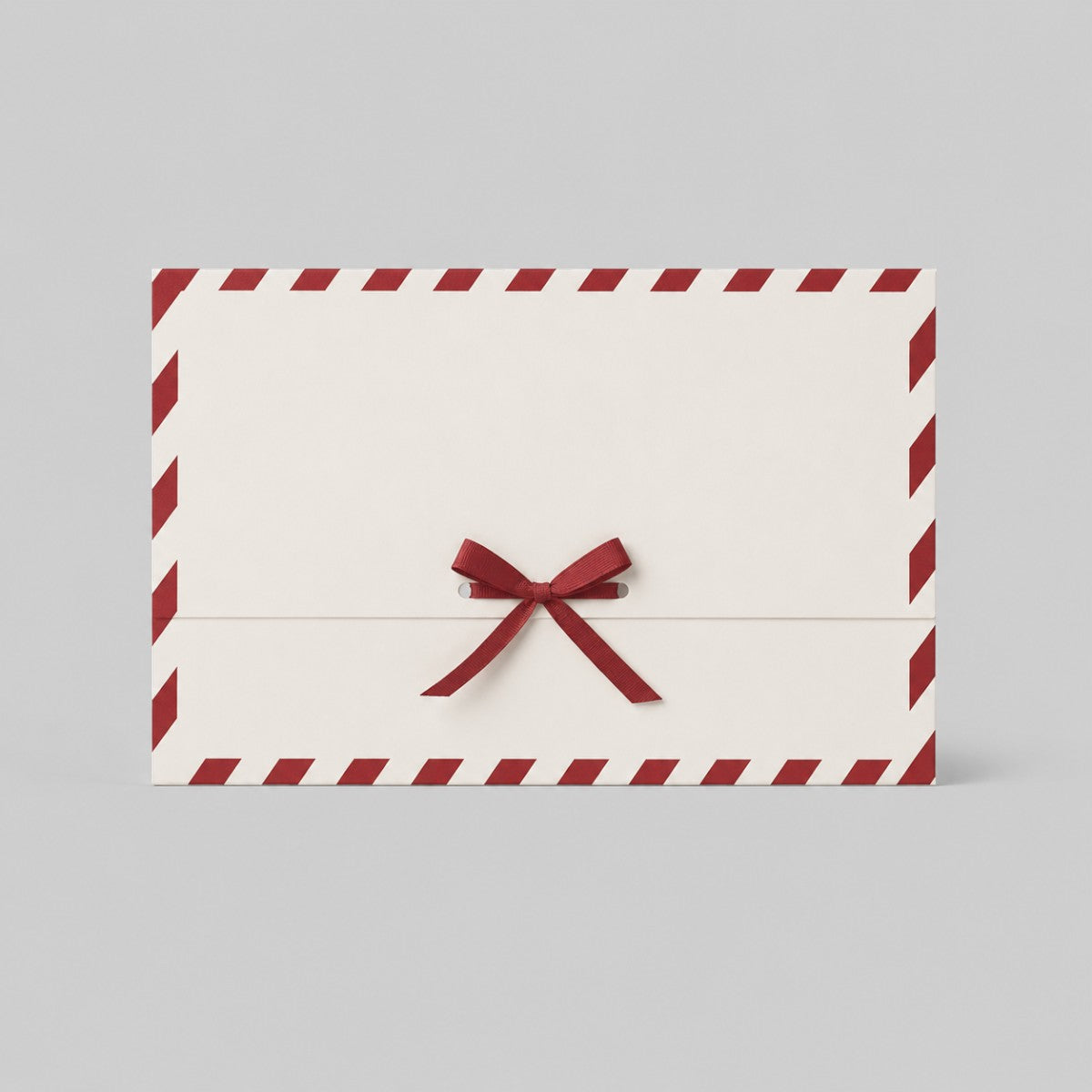 Stockka festive cream paper gift envelope with red diagonal border and red satin ribbon bow closure.