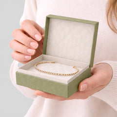 Stockka luxury green jewelry box with hinged lid, holding a gold tennis bracelet with clear stones. Interior lined with soft white fabric.
