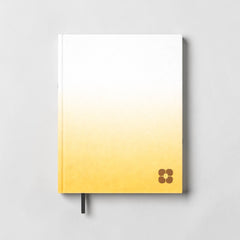 Stockka classic hard cover notebook with white to yellow gradient and brown flower logo. Features 80 lined pages and a bookmark.