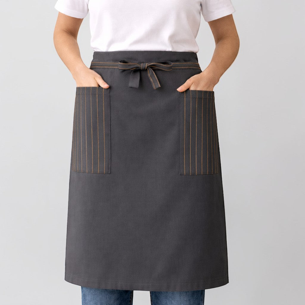 Stockka long dark grey cotton-polyester blend waist apron with two side pockets featuring pinstripe detail and a tie waist.