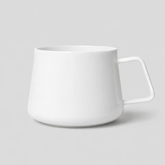 Stockka modern white ceramic mug with a unique geometric shape and an angular handle on a light grey background