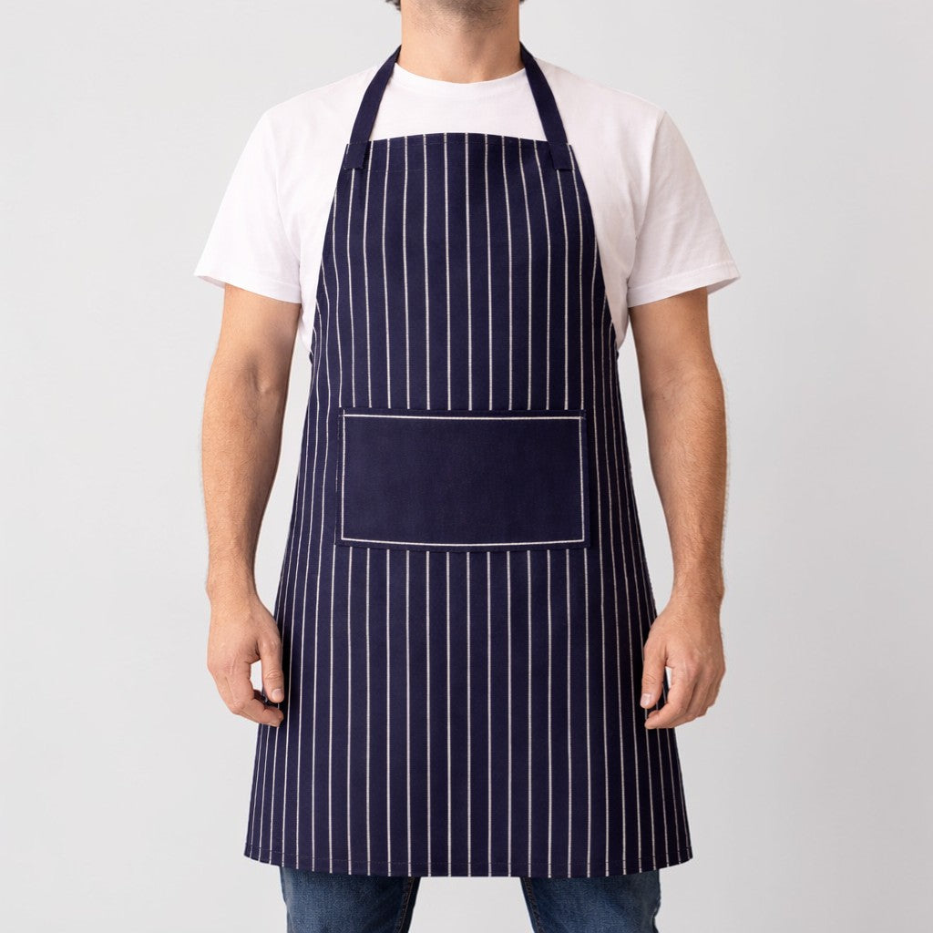 Stockka navy blue vertical stripe apron with adjustable neck strap and front pocket. Cotton-polyester blend.
