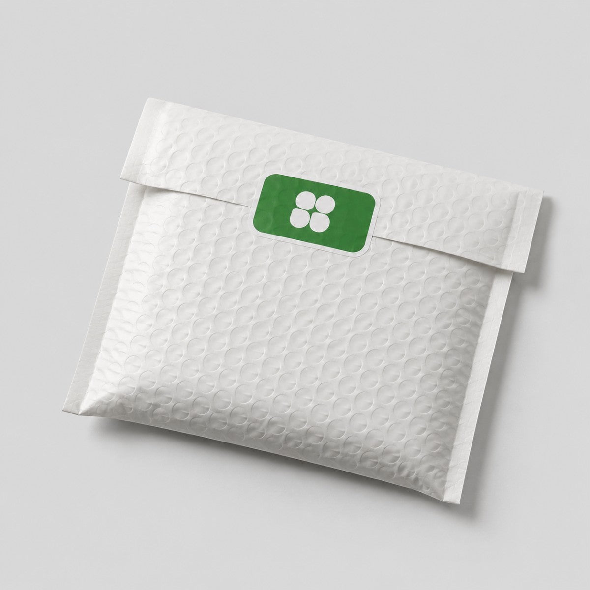 Stockka white padded envelope with rounded corner rectangular sticker featuring a green label with four white circles.
