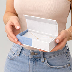 Stockka premium flat top-opening box with blue and white pattern, holding a delicate gold necklace with a single diamond.