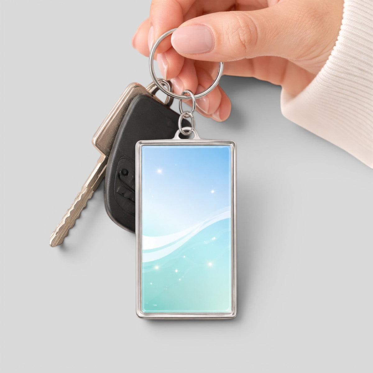Stockka rectangular acrylic keychain with metal ring, featuring a blue and teal gradient with wavy lines and sparkles.