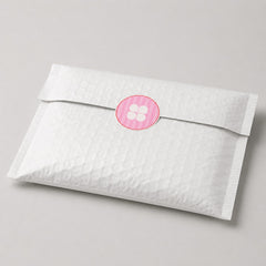 Stockka pink and white striped round sticker with a four-petal flower design on a white padded envelope.
